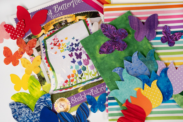Colorful fabric pieces, butterflies, and a quilt design titled A Butterfly Quilt arranged artistically.