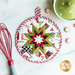 White, red, and green Christmas themed hot pad on a wood table