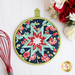 Round folded star hot pad on a white countertop with red and white roses and a red whisk nearby