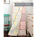 A colorful quilt titled Summer Nights drapes over a chair in a bright room with wooden furniture.