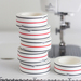 A stack of white tape rolls with black and red stripes, sitting on a flat surface near a sewing machine.