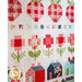 A colorful quilt featuring patterned designs of strawberries, flowers, and houses in shades of red, green, and blue, with a floral and checkered motif.