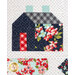 A quilted block featuring a house with a navy blue patterned roof, a red door, and floral designs in various colors. There are two chimney pieces at the top, and the background has a dotted pattern.