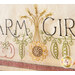 An embroidered textile featuring the words Farm Girl alongside decorative illustrations of a sunflower, peas, and tomatoes, with vibrant thread colors.