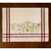 A decorative kitchen towel featuring the words FARM GIRL in bold lettering, surrounded by illustrations of vegetables like corn, tomatoes, and carrots. The towel has red striped borders and a scalloped edge.