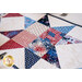 A close-up view of a red, white, and blue quilt featuring a star pattern with various fabric designs, including stripes, polka dots, and fireworks.