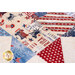 A close-up view of a patchwork quilt featuring red, white, and blue fabrics with various patriotic designs, including stars, stripes, and images of the Statue of Liberty. The quilt displays a mix of patterns and textures, celebrating a festive theme.