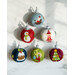 Six decorative Christmas ornaments are arranged on a light-colored surface. The ornaments feature various festive designs, including a snowman, Santa in a sleigh, a Christmas tree, and other holiday motifs, each in vibrant colors of red, green, blue, and white.