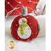 A red Christmas ornament shaped like a snowman, featuring a white snowman with a green scarf and orange carrot nose, adorned with small decorations and a silver hanging ribbon. The background is softly blurred with holiday colors.