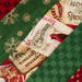 A close-up of a patchwork fabric featuring various festive Christmas designs, including red and green patterns, snowflakes, and vintage holiday postcards.