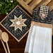 Star design hot pad and hand towel displayed on table.