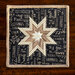 Square quilted hot pad with star design and wording pattern.