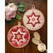 A set of two round hot pads, one made with white floral fabrics and one made with red.