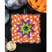 Square hot pad with central folded star design featuring Halloween themed fabrics.