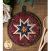 Red hot pad with central folded star designs and navy fabric resting on a wood table.