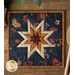 Dark blue hot pad with central folded star designs and navy fabric resting on a wood table.