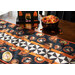 Halloween themed table runner featuring retro styled Halloween motifs and white and black pinwheel stripe.