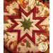 Round autumn themed floral hot pad with a central folded star design on wooden table.