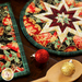 Round black hot pad with Christmas ornament prints and central folded star design.