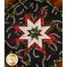 Square hot pad made of black fabric with tossed horseshoes and holly featuring a central folded star.