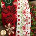 Hanging holiday stocking made from strips of Christmas themed fabric in red, green, and white.