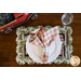 Christmas themed scalloped placemat featuring red trucks, wagons, and pine trees as part of a table setting with a plate and cloth napkin.