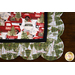 Christmas themed scalloped placemat featuring red trucks, wagons, and pine trees.