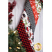 Hanging holiday stocking made from strips of Christmas themed fabric in red, black, and white.