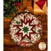 Round cream hot pad featuring holiday phrases and central folded star design on wood table.