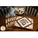 Coffee themed placemats made of brown, tan, and cream fabrics with coffee cups in the center surrounded by strips of fabric in a diamond shape.