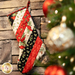 Hanging holiday stocking made from strips of Christmas themed fabric in red, black, and white.