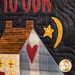 A close-up of a colorful fabric quilt featuring a house with a heart, a yellow star, and a crescent moon on a dark background. The words TO OUR are embroidered at the top in red.