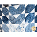 Quilt featuring flower petal shaped piecing of tonal blue batik fabric.