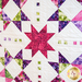 A quilt with geometric square and triangle designs made of multicolor fabrics on white.