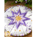 Round hot pad with central folded star design made of purple and white floral printed fabrics.