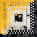 Wall hanging block made of strips of bee themed and floral fabrics in white, black, and yellow.