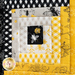 Wall hanging block made of strips of bee themed and floral fabrics in white, black, and yellow.