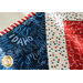 Table runner with central diamond design and angled strips at the ends made of patriotic printed fabrics.