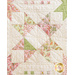 Quilt block with geometric square and triangle designs made of pastel color fabrics on white.