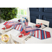 Table runner made of strips of alternating diagonal fabrics in red, white, and blue featuring patriotic motifs.