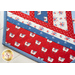 Table runner made of strips of alternating diagonal fabrics in red, white, and blue featuring patriotic motifs.