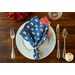 Reversible cloth napkin, one side printed with sheep wearing a US flag on blue, the other with red and white gingham.