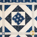 Quilt with geometric designs of squares and diamonds in blue and cream fabrics.