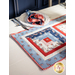 Table runner with square designs made with strips of red, white, and blue fabric featuring floral, paisley, and gingham prints.