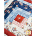 Table runner with square designs made with strips of red, white, and blue fabric featuring floral, paisley, and gingham prints.