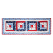 Table runner with square designs made with strips of red, white, and blue fabric featuring floral, paisley, and gingham prints.