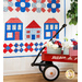 Quilt with rows of designs including stars, flags, houses, flowers, and various geometric shapes all made of red, white, and blue fabric,