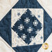 Close-up of a quilt block featuring a dark blue star pattern on a light fabric background.