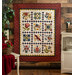 A colorful quilt features floral and bird patterns set against a red and white backdrop.