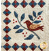 Appliqué quilt featuring a red bird on a branch surrounded by blue leaves and decorative squares.